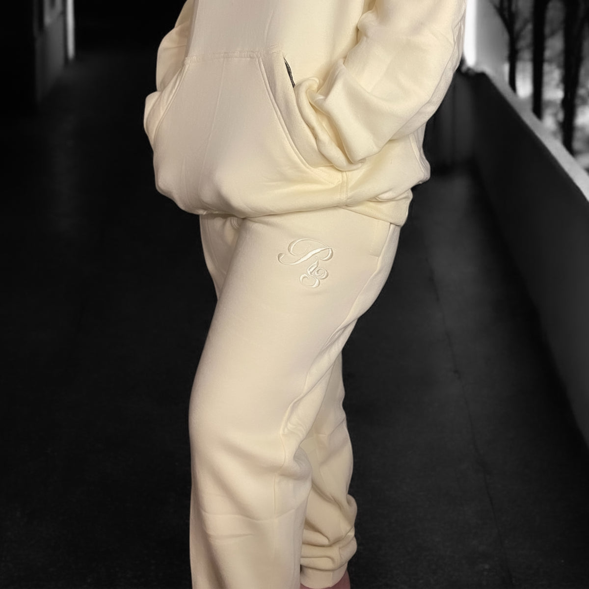 A close-up of a person wearing gray Coz3 Max Unisex Sweatpants, showing the side pocket and the brand's logo on the leg of the pants.